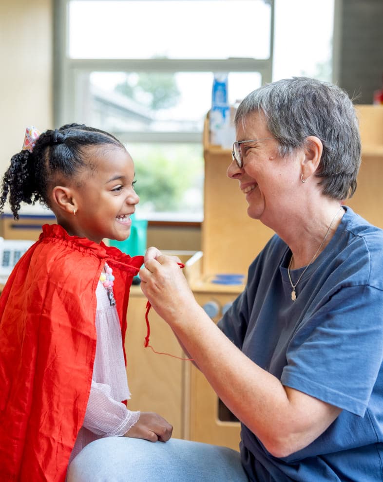 Kind speelt met verkleedkleding samen met pedagogisch medewerker bij kinderopvang Kind&co ludens