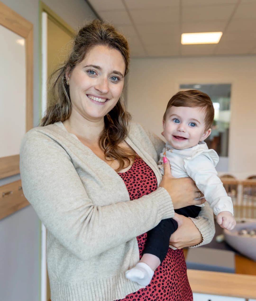 Baby wordt geknuffeld door pedagogisch medewerker bij kinderopvang Kind&co ludens