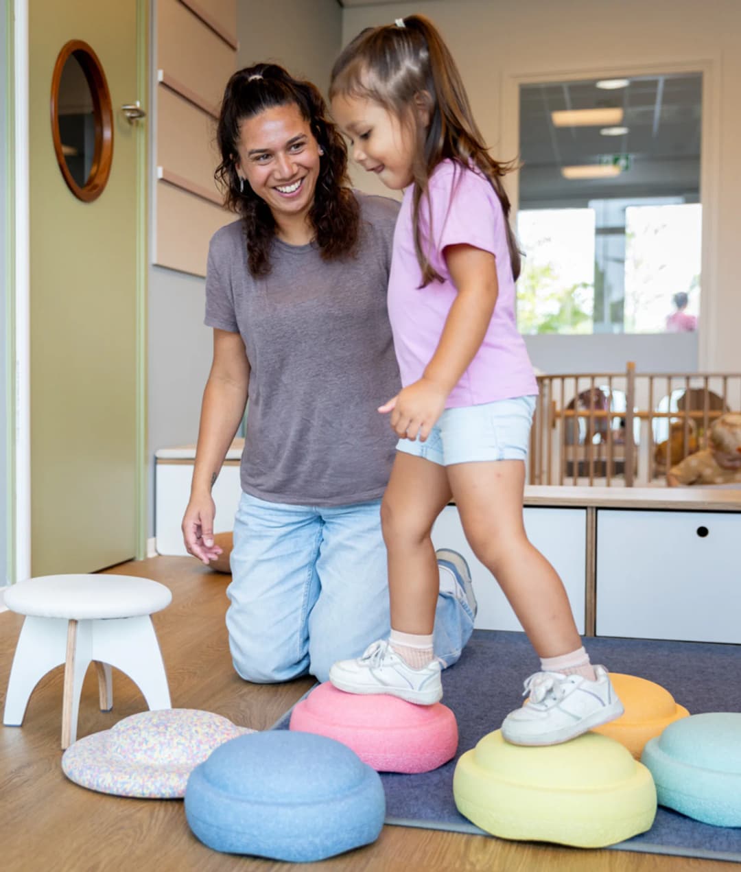 Kinderen spelen samen met pedagogisch medewerker met stapelstenen bij kinderopvang Kind&co ludens