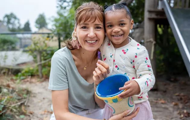 Kind speelt buiten met pedagogisch medewerker bij kinderopvang Kind&co ludens